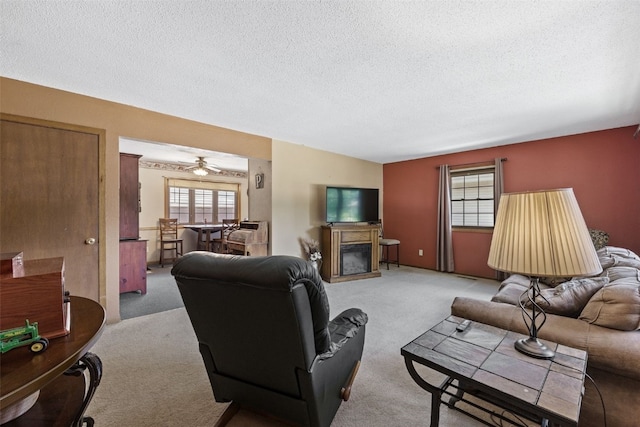 2540 Lori Dr SW, Cedar Rapids, IA 52404 - living area with carpet flooring, a textured ceiling, a glass covered fireplace, and a ceiling fan