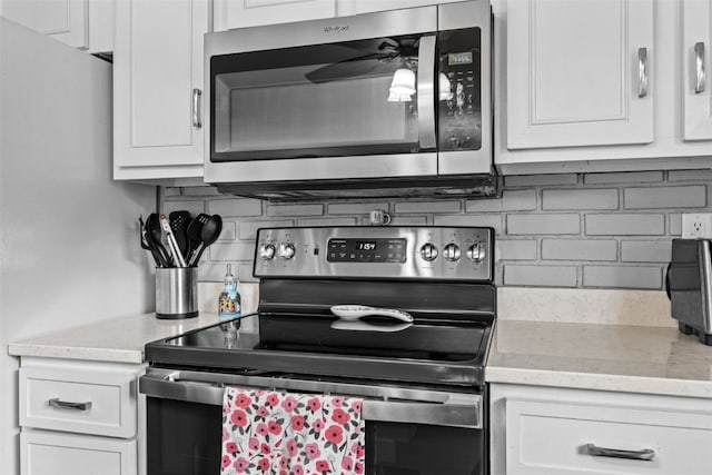 1428 Timber Ridge Trl NE, Solon, IA 52333 - kitchen featuring appliances with stainless steel finishes, tasteful backsplash, white cabinetry, a ceiling fan, and light stone countertops