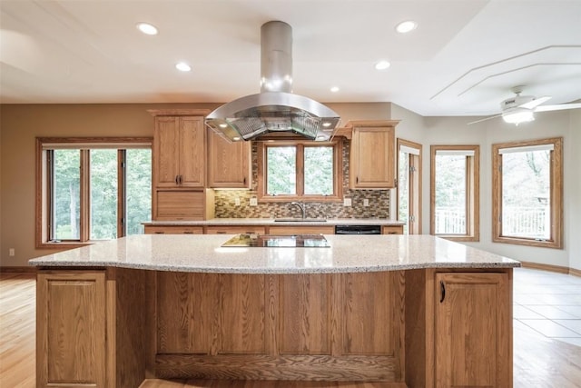 3519 Timber Ridge Trl NE, Cedar Rapids, IA 52411 - kitchen with island range hood, a large island, backsplash, black appliances, and light stone counters