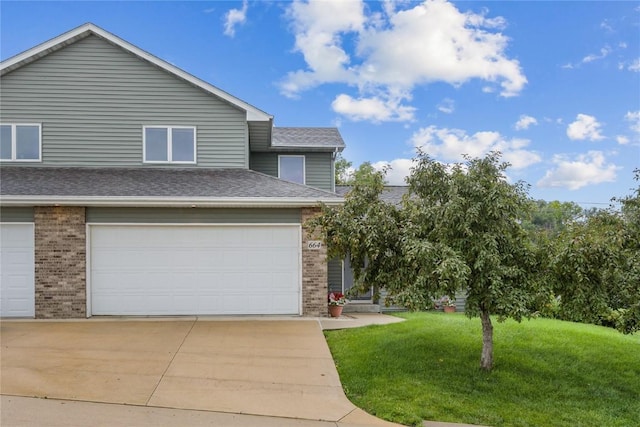664 J Ave NE Unit A, Cedar Rapids, IA 52402 - view of front facade featuring brick siding, a front yard, concrete driveway, and a shingled roof