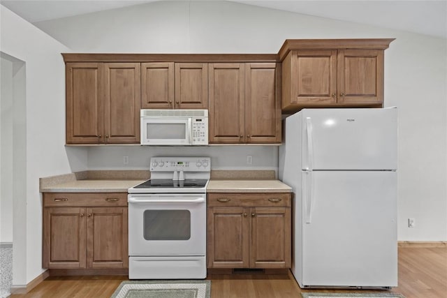 664 J Ave NE Unit A, Cedar Rapids, IA 52402 - kitchen with white appliances, light wood finished floors, lofted ceiling, light countertops, and brown cabinets