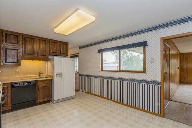 5660 Briarwood St SW, Cedar Rapids, IA 52401 - kitchen featuring white refrigerator with ice dispenser, black dishwasher, light countertops, and wallpapered walls