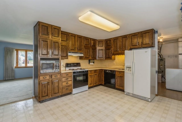 5660 Briarwood St SW, Cedar Rapids, IA 52401 - kitchen with white appliances, under cabinet range hood, light countertops, light carpet, and brown cabinets
