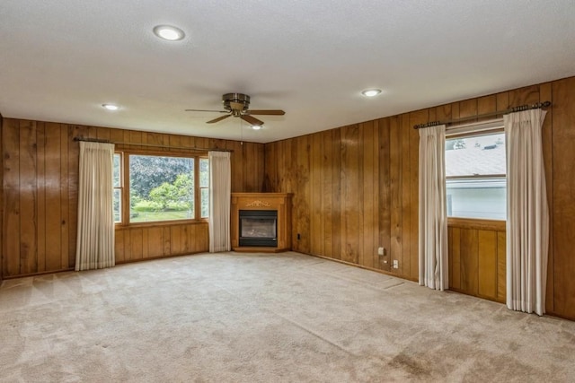 5660 Briarwood St SW, Cedar Rapids, IA 52401 - unfurnished living room with a ceiling fan, light carpet, a glass covered fireplace, wooden walls, and recessed lighting