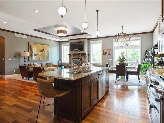 4390 Flagstick Dr, Marion, IA 52302 - kitchen with stainless steel dishwasher, ornamental molding, a tray ceiling, open floor plan, and light wood-style flooring