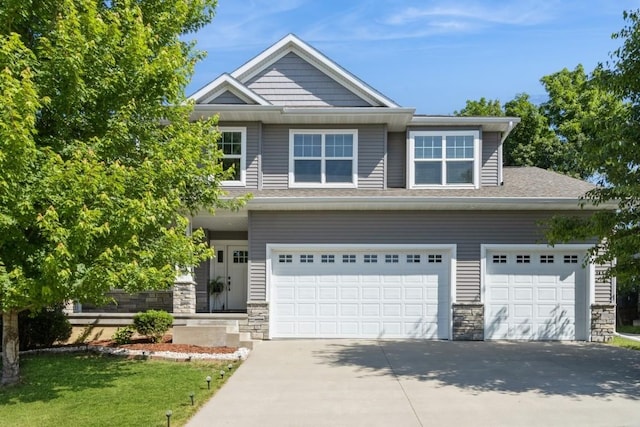 3076 Lower W Branch Rd, Iowa City, IA 52245 - view of front of house with concrete driveway, stone siding, an attached garage, and a front yard
