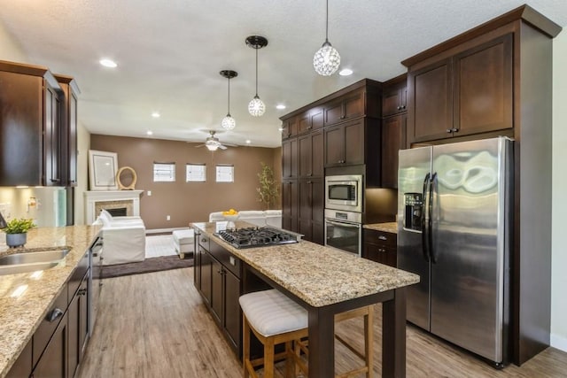 3076 Lower W Branch Rd, Iowa City, IA 52245 - kitchen with appliances with stainless steel finishes, dark brown cabinetry, open floor plan, recessed lighting, and hanging light fixtures