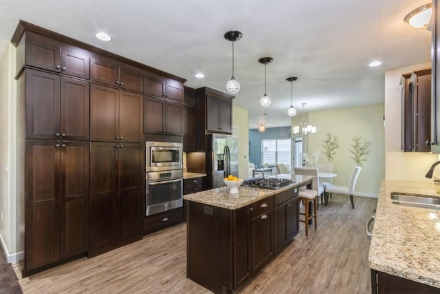 3076 Lower W Branch Rd, Iowa City, IA 52245 - kitchen with stainless steel appliances, light wood finished floors, a kitchen island, dark brown cabinets, and recessed lighting