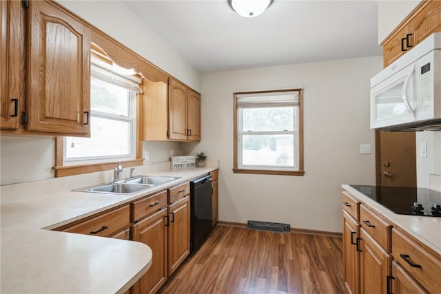 3624 Bel Air Dr SE, Cedar Rapids, IA 52403 - kitchen with white microwave, dishwasher, wood finished floors, light countertops, and brown cabinets
