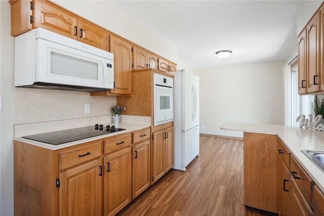 3624 Bel Air Dr SE, Cedar Rapids, IA 52403 - kitchen featuring white appliances, light wood-style floors, light countertops, and brown cabinets