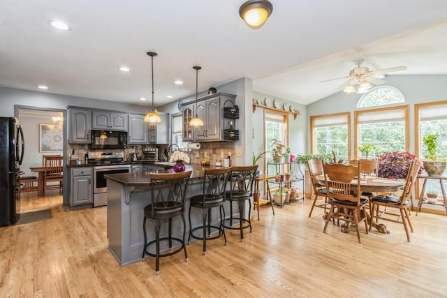 2815 Oak Crest Ct NW, Cedar Rapids, IA 52405 - kitchen featuring black appliances, gray cabinets, a peninsula, dark countertops, and a breakfast bar