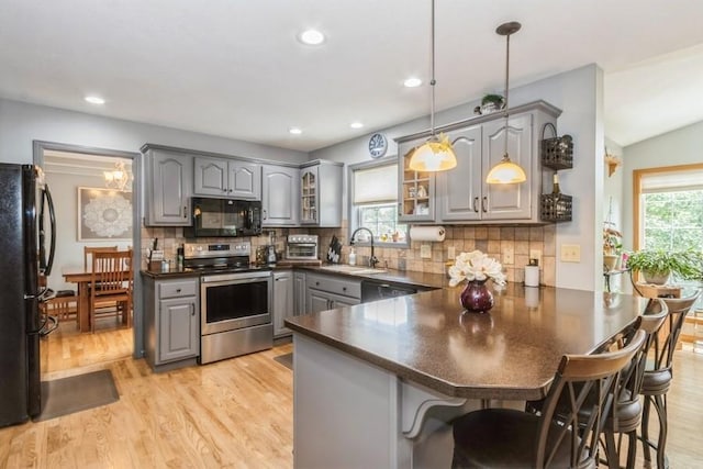 2815 Oak Crest Ct NW, Cedar Rapids, IA 52405 - kitchen featuring black appliances, gray cabinets, a peninsula, dark countertops, and glass insert cabinets