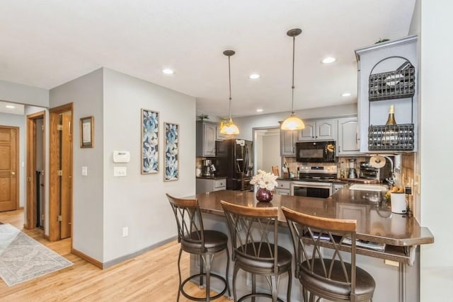 2815 Oak Crest Ct NW, Cedar Rapids, IA 52405 - kitchen featuring black appliances, dark countertops, a peninsula, gray cabinetry, and light wood-style flooring