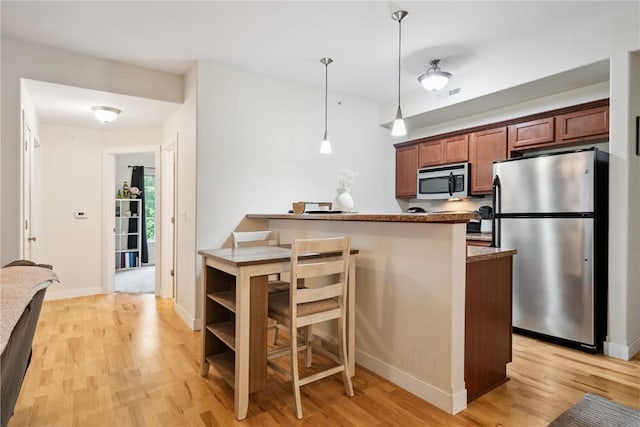 1848 W Benton St, Iowa City, IA 52246 - kitchen with appliances with stainless steel finishes, light wood-style floors, pendant lighting, a breakfast bar area, and a peninsula