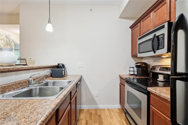 1848 W Benton St, Iowa City, IA 52246 - kitchen featuring stainless steel appliances, light wood-type flooring, brown cabinetry, light countertops, and decorative light fixtures