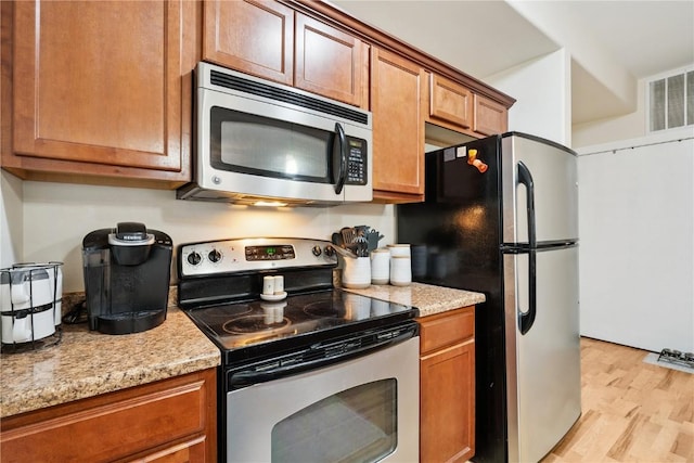 1848 W Benton St, Iowa City, IA 52246 - kitchen with appliances with stainless steel finishes, light wood finished floors, and brown cabinetry