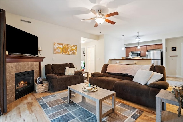 1848 W Benton St, Iowa City, IA 52246 - living area with light wood-type flooring, a ceiling fan, and a tiled fireplace