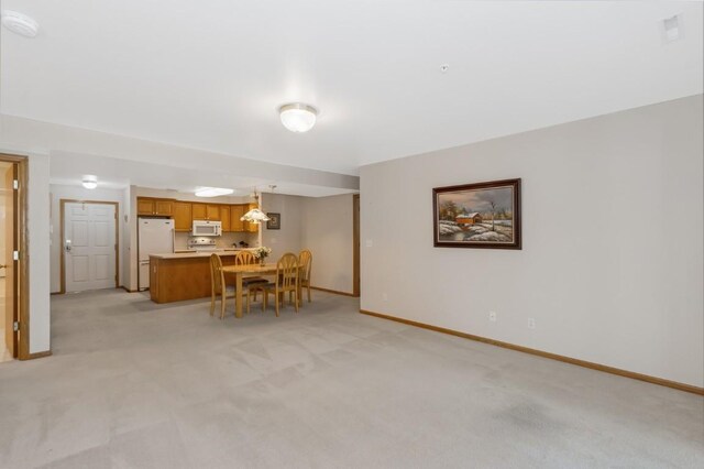 2601 Hickory Trl Unit 1, Iowa City, IA 52245 - kitchen with white appliances, light colored carpet, a peninsula, brown cabinets, and a breakfast bar
