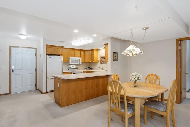 2601 Hickory Trl Unit 1, Iowa City, IA 52245 - kitchen featuring white appliances, a peninsula, light colored carpet, light countertops, and brown cabinets