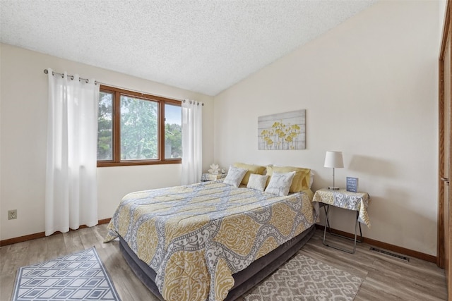 2060 Holiday Rd, Coralville, IA 52241 - bedroom featuring a textured ceiling, lofted ceiling, and wood finished floors
