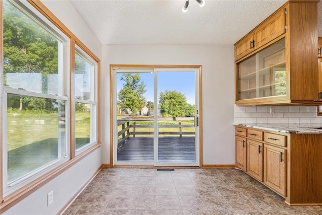 705 Grant Wood Dr SE, Cedar Rapids, IA 52403 - kitchen featuring plenty of natural light, backsplash, a textured ceiling, and brown cabinets