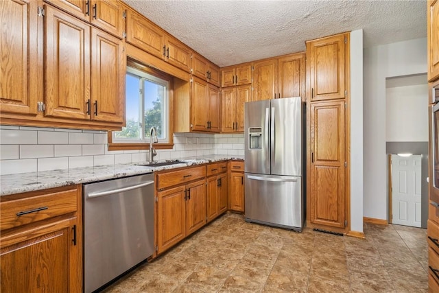 705 Grant Wood Dr SE, Cedar Rapids, IA 52403 - kitchen with stainless steel appliances, decorative backsplash, brown cabinets, light stone countertops, and a textured ceiling