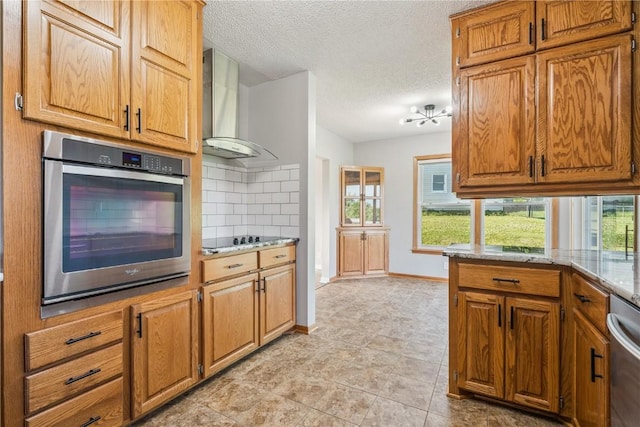 705 Grant Wood Dr SE, Cedar Rapids, IA 52403 - kitchen featuring stainless steel appliances, wall chimney exhaust hood, tasteful backsplash, a textured ceiling, and brown cabinetry