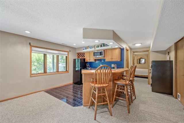 3496 E Otter Rd, Marion, IA 52302 - kitchen featuring stainless steel microwave, carpet floors, freestanding refrigerator, a textured ceiling, and a kitchen breakfast bar