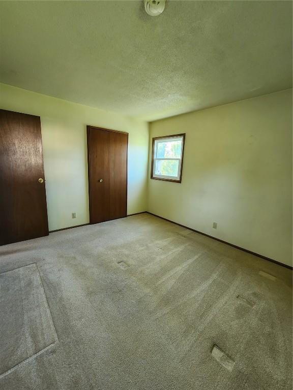 339 Fleetwood Rd SW, Cedar Rapids, IA 52404 - unfurnished bedroom featuring light colored carpet, a closet, and a textured ceiling