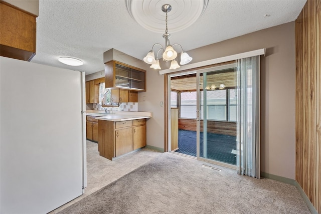425 28th St NW, Cedar Rapids, IA 52405 - kitchen with freestanding refrigerator, light countertops, a textured ceiling, a peninsula, and brown cabinets