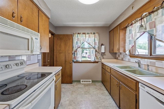 425 28th St NW, Cedar Rapids, IA 52405 - kitchen with white appliances, brown cabinetry, light countertops, and a textured ceiling