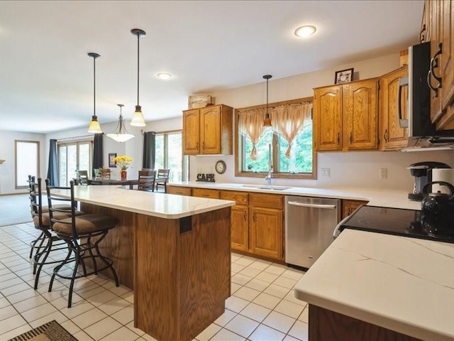 2066 Vista Cir NW, Cedar Rapids, IA 52405 - kitchen with appliances with stainless steel finishes, a breakfast bar area, a kitchen island, brown cabinets, and light countertops