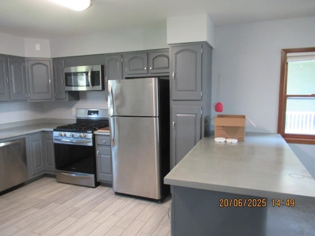 302 Meridian St, Tipton, IA 52772 - kitchen featuring stainless steel appliances, gray cabinets, light countertops, and light wood finished floors