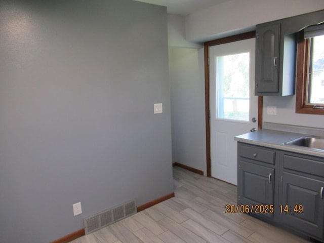 302 Meridian St, Tipton, IA 52772 - kitchen with gray cabinetry, light wood-style floors, and light countertops