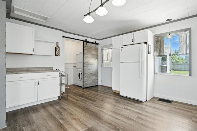 1635 Keith Dr NE, Cedar Rapids, IA 52402 - kitchen with freestanding refrigerator, a barn door, washer / dryer, white cabinets, and dark wood-style flooring