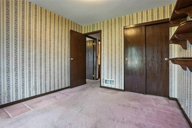 4121 Lexington Dr NE Unit B, Cedar Rapids, IA 52402 - unfurnished bedroom featuring wallpapered walls, carpet flooring, a closet, and a textured ceiling