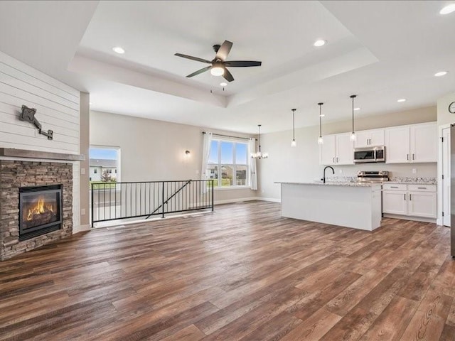 1326 Echo Ridge Ln, Marion, IA 52302 - unfurnished living room featuring a tray ceiling, dark wood-type flooring, ceiling fan, recessed lighting, and a stone fireplace