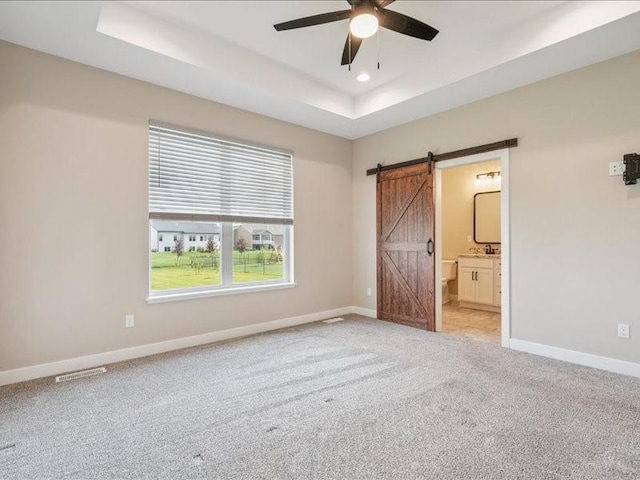 1326 Echo Ridge Ln, Marion, IA 52302 - unfurnished bedroom featuring a barn door, a raised ceiling, light carpet, connected bathroom, and recessed lighting