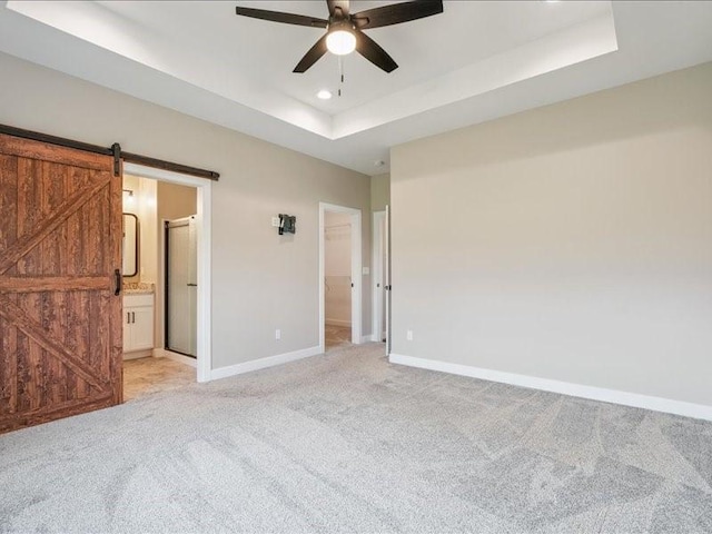 1326 Echo Ridge Ln, Marion, IA 52302 - unfurnished bedroom with light carpet, a barn door, a tray ceiling, recessed lighting, and ensuite bath