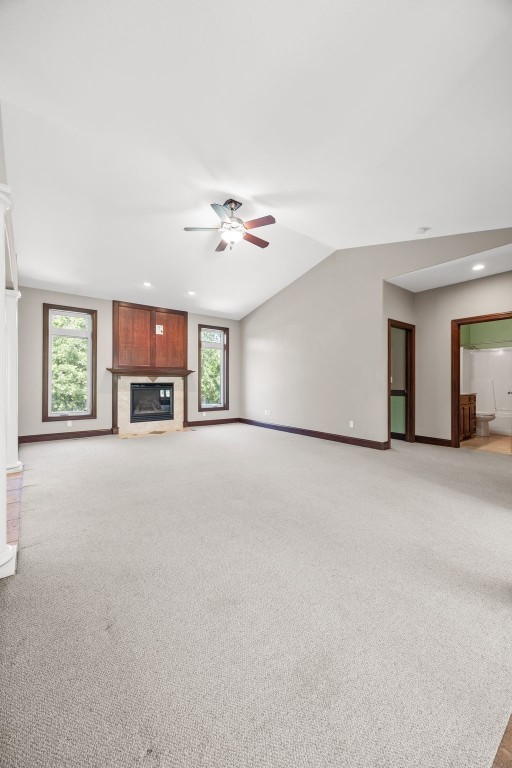 4452 Plumberry Rd, Ely, IA 52227 - unfurnished living room featuring ceiling fan, a glass covered fireplace, light colored carpet, and vaulted ceiling