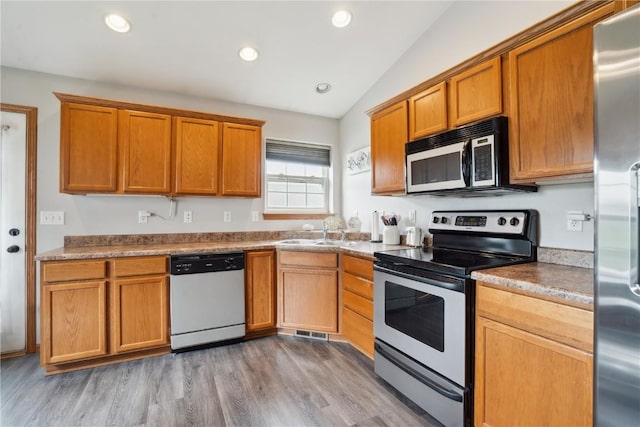1727 Hunters Creek Way, Marion, IA 52302 - kitchen featuring stainless steel appliances, vaulted ceiling, light wood-style flooring, brown cabinetry, and recessed lighting