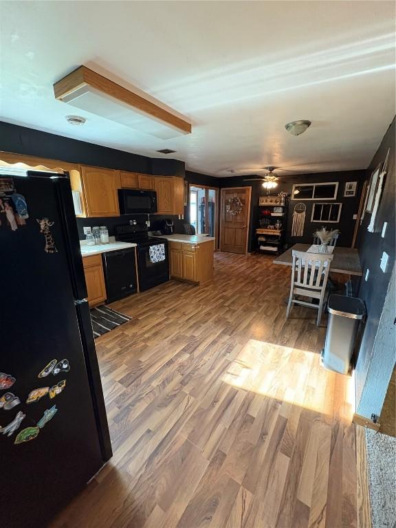 21 Mill St, Walker, IA 52352 - kitchen with black appliances, light countertops, light wood-style flooring, and a peninsula