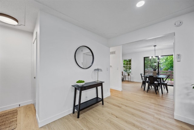 1642 19th St, Cedar Rapids, IA 52405 - hallway with light wood-type flooring and a chandelier