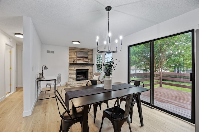 1642 19th St, Cedar Rapids, IA 52405 - dining area featuring a fireplace, light wood-style floors, a textured ceiling, and a chandelier