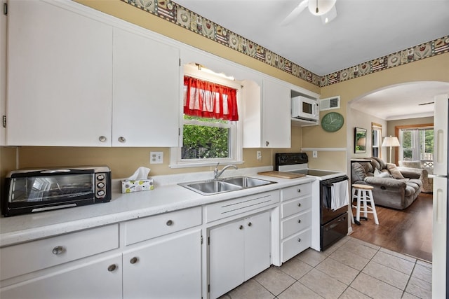913 32nd St SE, Cedar Rapids, IA 52403 - kitchen featuring electric range, white microwave, arched walkways, light countertops, and white cabinets