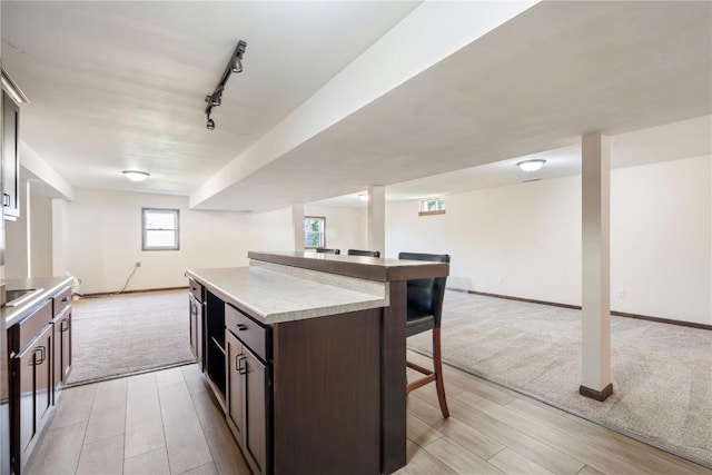 6752 29th Ave, Shellsburg, IA 52332 - kitchen with open floor plan, a kitchen breakfast bar, light colored carpet, dark brown cabinets, and a center island