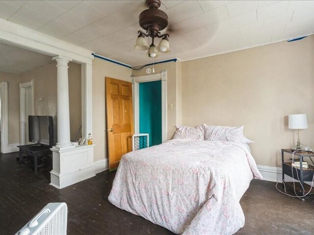 1551 C Ave NE, Cedar Rapids, IA 52402 - bedroom featuring decorative columns, hardwood / wood-style flooring, and a ceiling fan