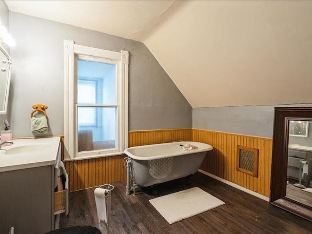 1551 C Ave NE, Cedar Rapids, IA 52402 - bathroom featuring vanity, wainscoting, wood finished floors, vaulted ceiling, and a soaking tub