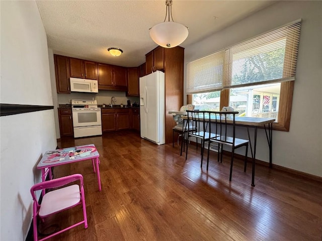 72 Fleetwood Rd NW, Cedar Rapids, IA 52405 - kitchen featuring white appliances, dark wood-type flooring, dark countertops, and hanging light fixtures