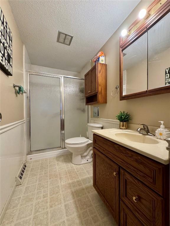 72 Fleetwood Rd NW, Cedar Rapids, IA 52405 - full bathroom featuring vanity, a textured ceiling, a stall shower, and a wainscoted wall